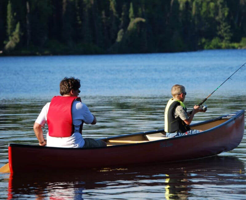 Two Garden Island guests enjoy fishing near the lodge in a canoe.